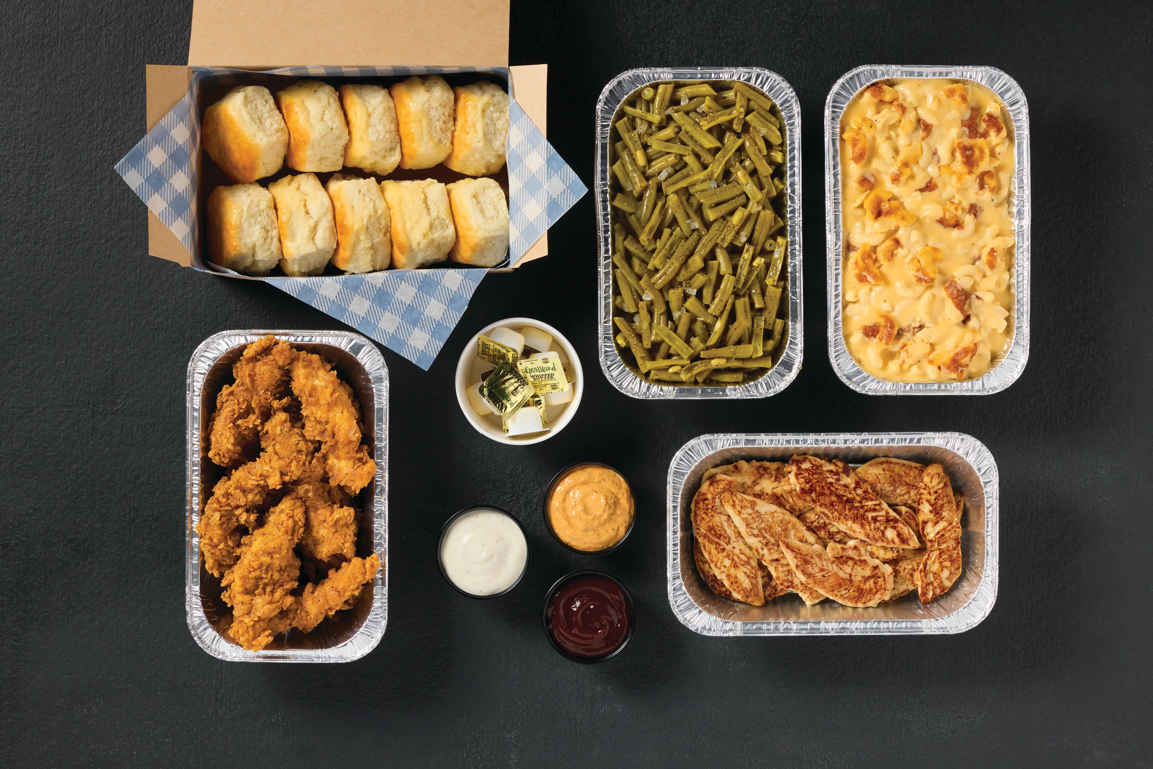 Grilled chicken tenders and crispy chicken tenders family meal with sides and biscuits.